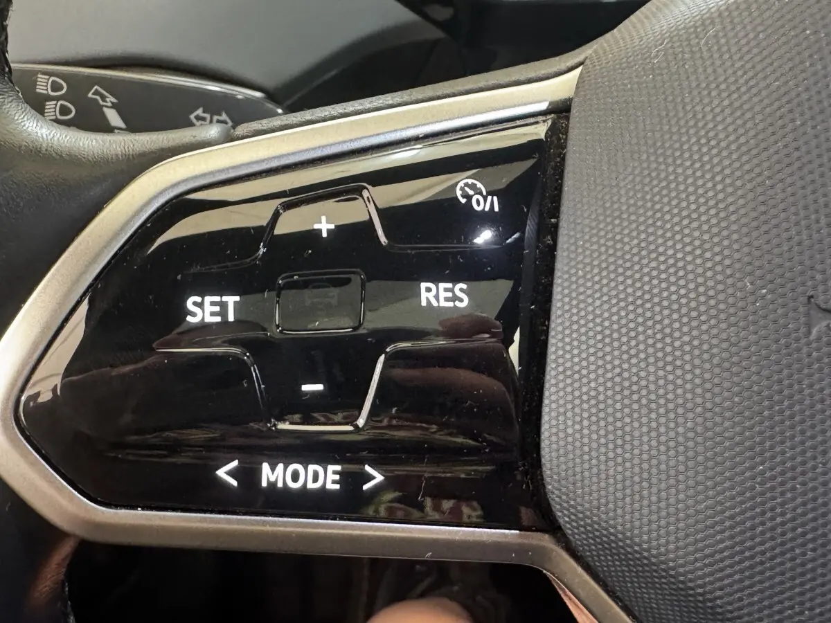 Gros plan sur les commandes du régulateur de vitesse au volant du Volkswagen ID.4 blanc, version 77 kWh Pro Performance.