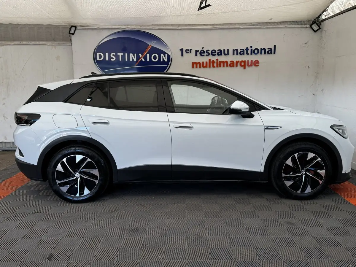 Vue de profil côté gauche d'un Volkswagen ID.4 blanc avec toit noir et jantes noires à motifs argentés.
