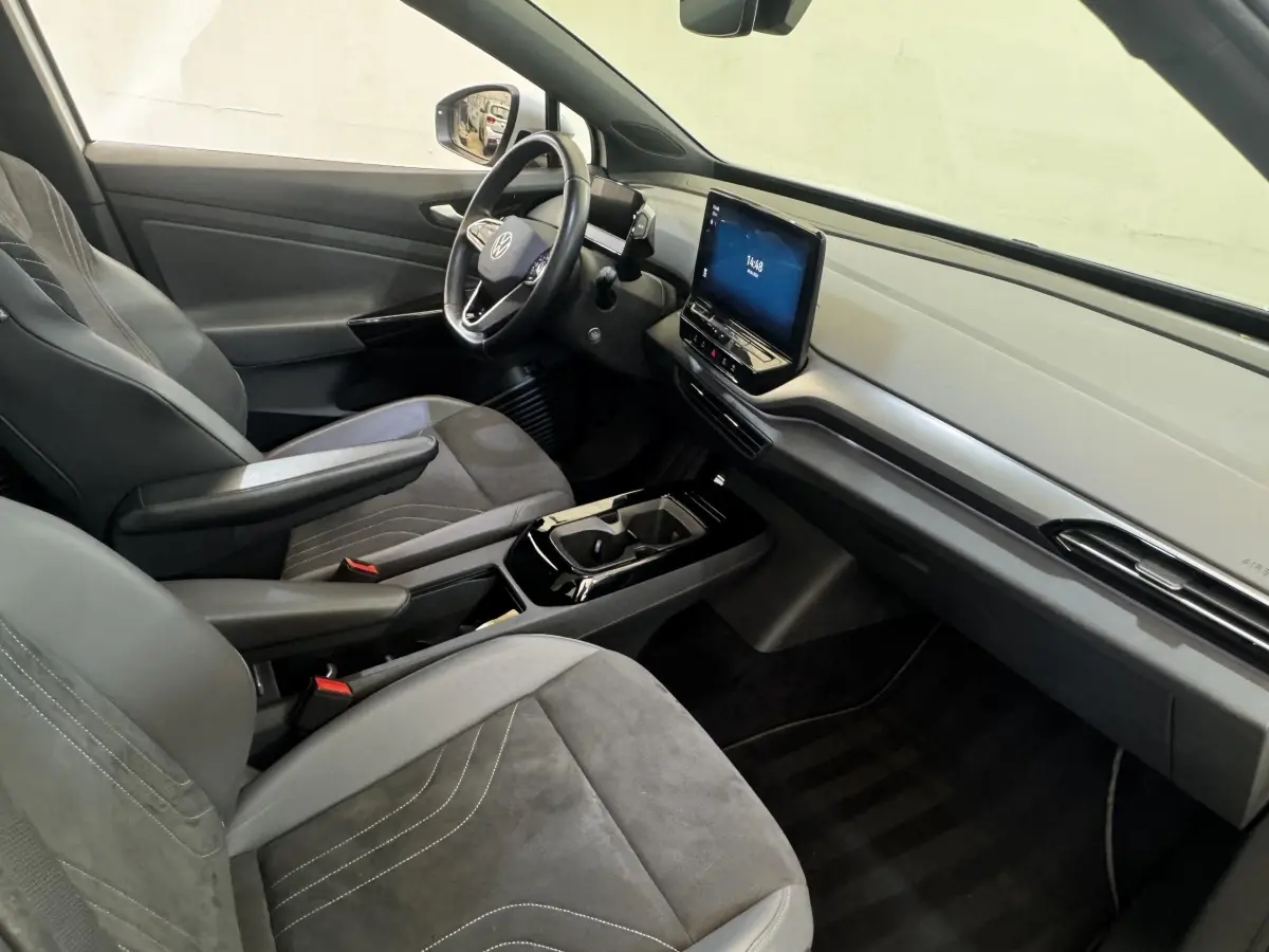 Vue intérieure côté conducteur du Volkswagen ID.4 blanc, avec tableau de bord épuré et écran tactile central.
