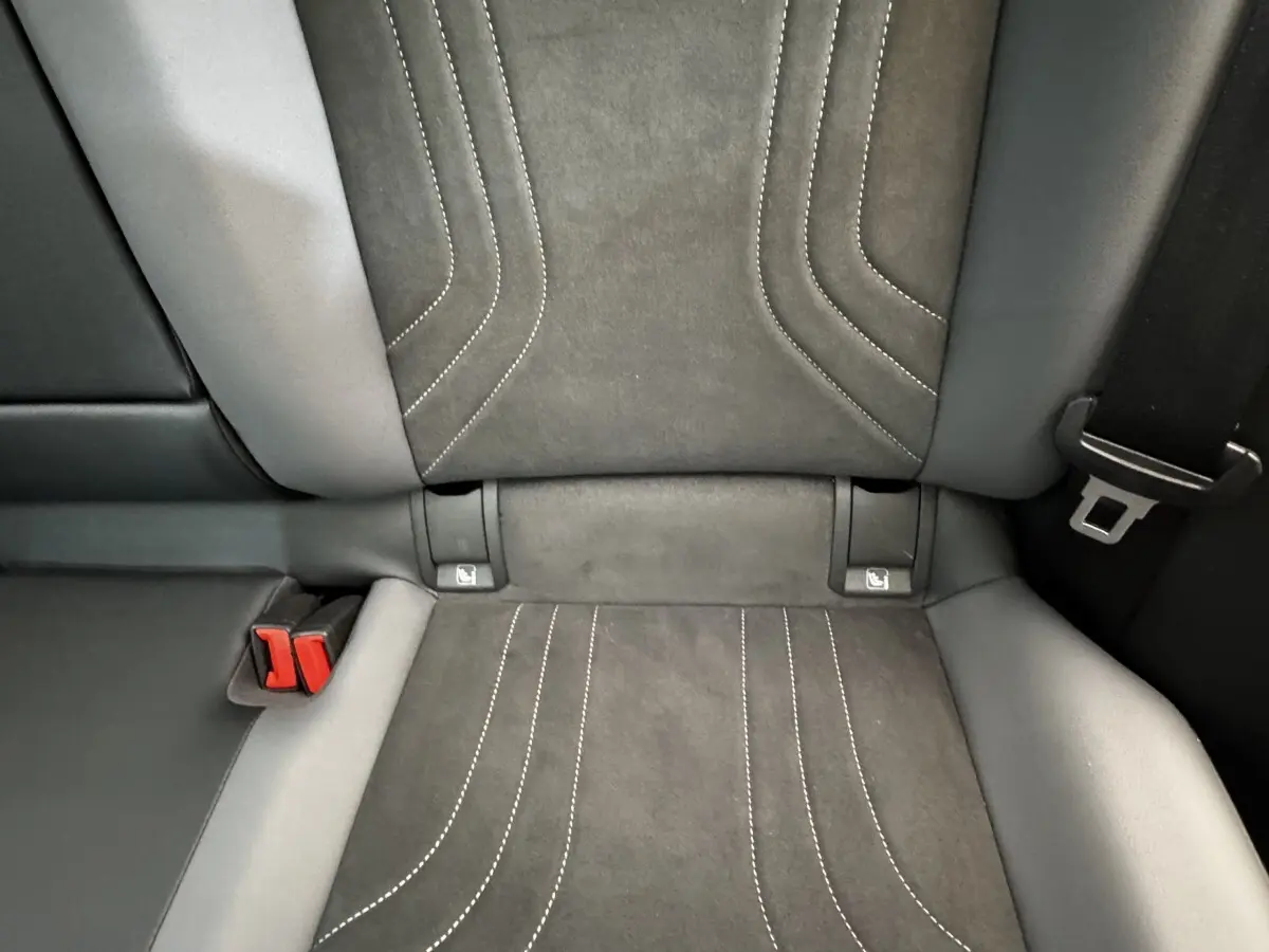 Gros plan sur la banquette arrière en tissu gris foncé avec coutures blanches et ceintures de sécurité rouges du Volkswagen ID.4.