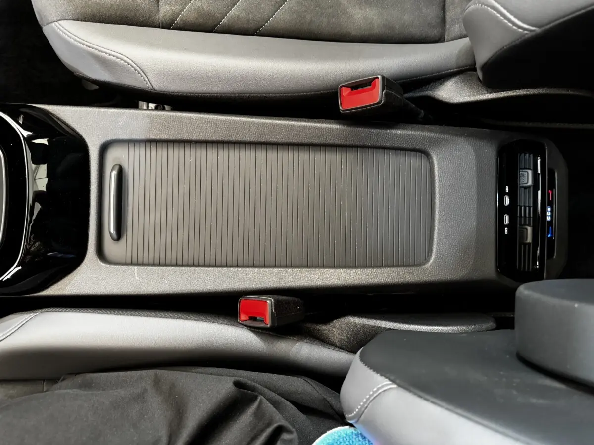 Vue plongeante sur la console centrale noire du Volkswagen ID.4 blanc, avec ceintures rouges et commandes climatisation arrière.