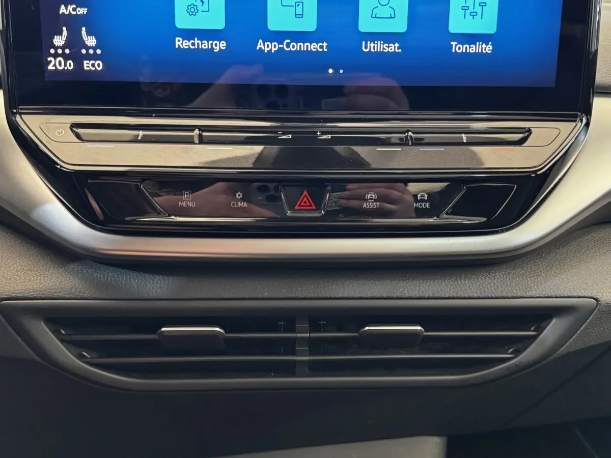 Gros plan sur la console centrale noire du Volkswagen ID.4 avec écran tactile et commandes tactiles sous l'écran.