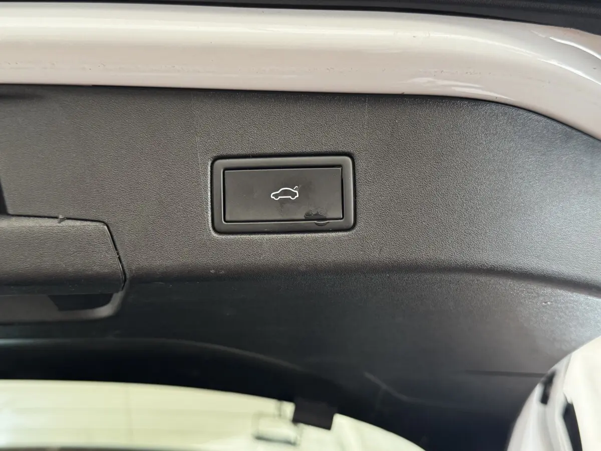 Gros plan sur le bouton d'ouverture électrique du coffre, intérieur noir du hayon du Volkswagen ID.4 blanc.