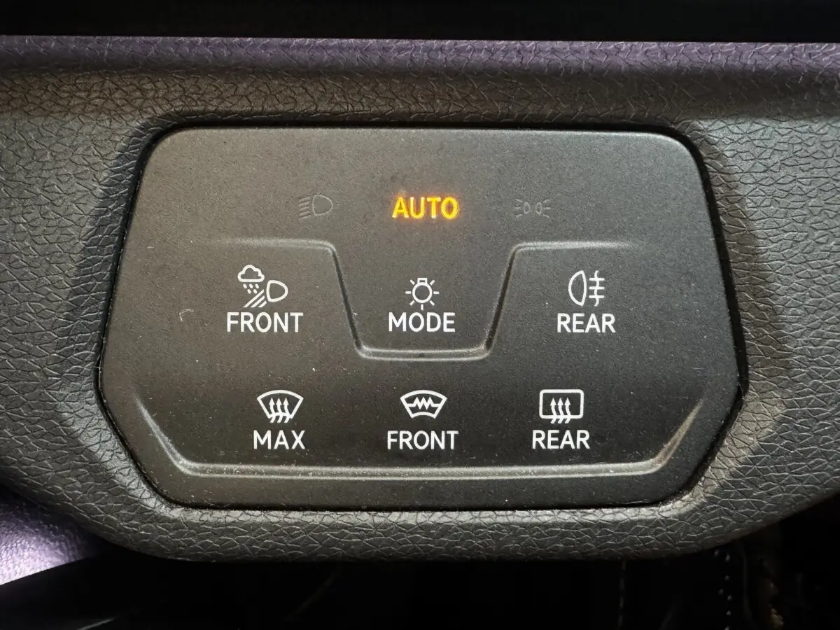 Gros plan sur le panneau de commande noir avec éclairage orange AUTO dans un Volkswagen ID.4 blanc.