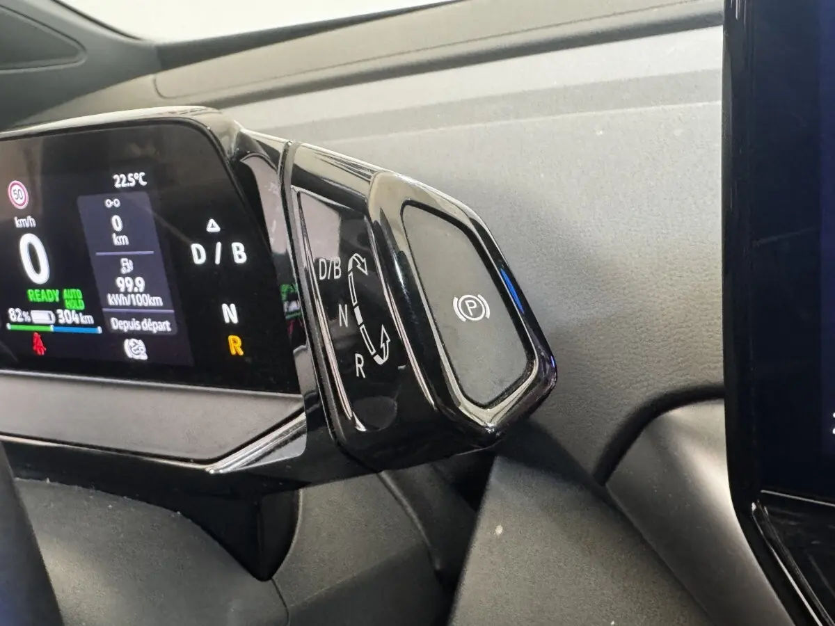 Gros plan sur la commande de boîte automatique noire et l’écran digital du tableau de bord du Volkswagen ID.4 blanc.
