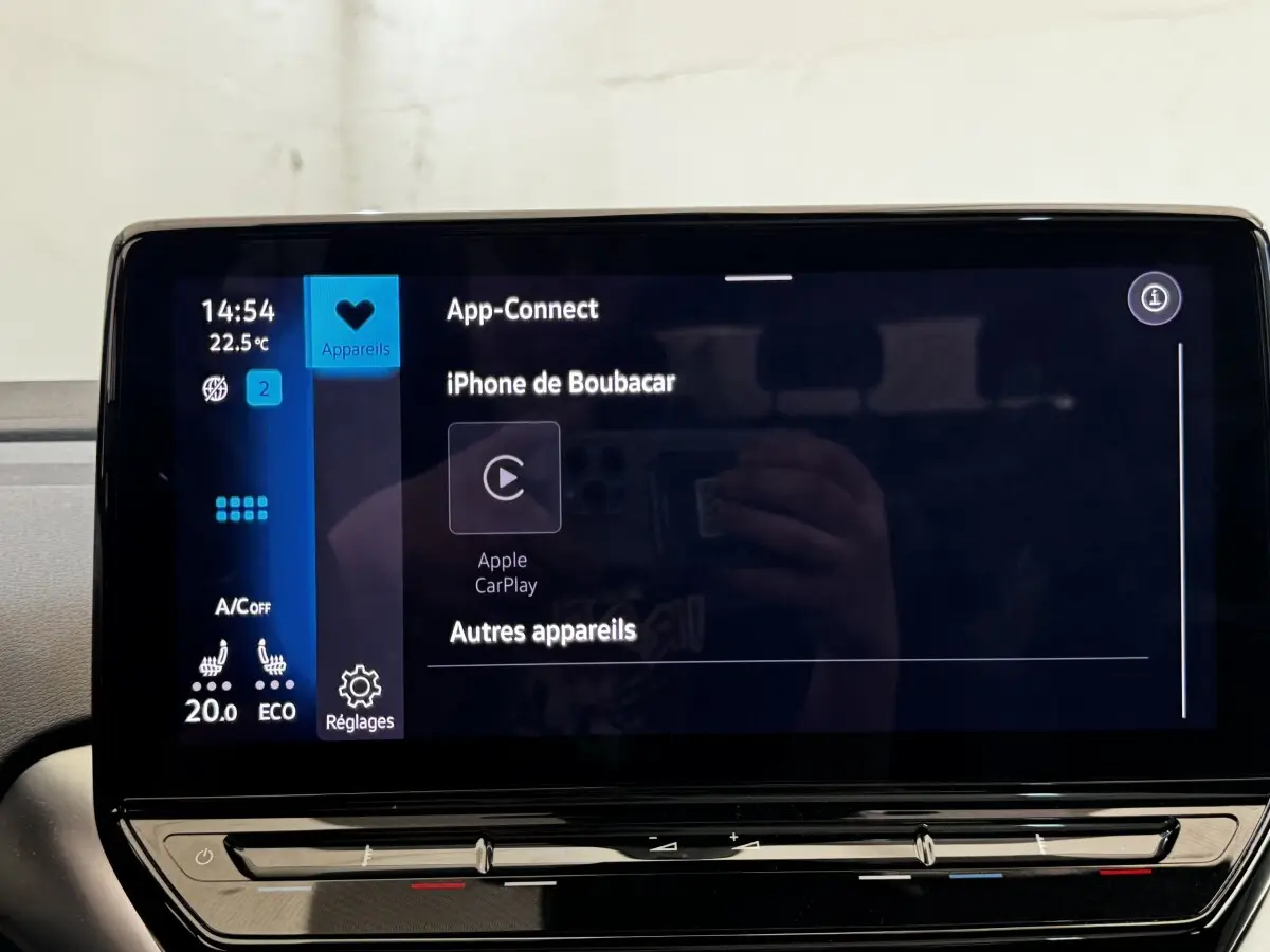 Écran tactile central du Volkswagen ID.4 blanc, affichant la connexion Apple CarPlay et les réglages climatisation.