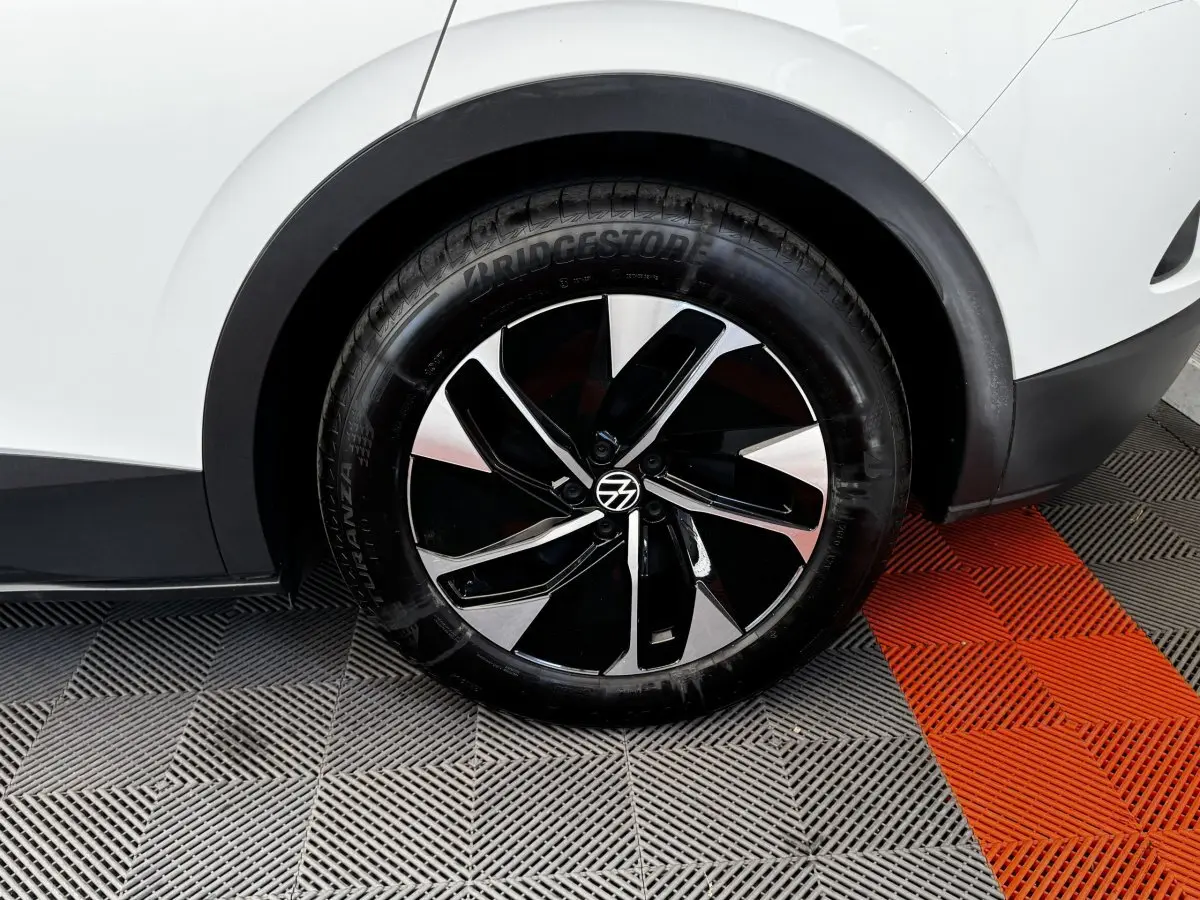 Gros plan sur la roue arrière droite noire et argentée du Volkswagen ID.4 blanc, avec partie de la carrosserie visible.