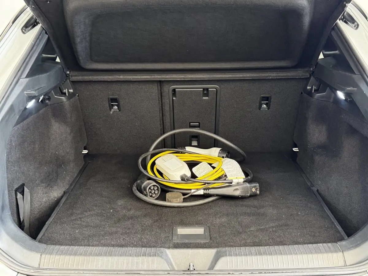Coffre ouvert d’un Volkswagen ID.4 blanc, vue intérieure montrant un câble de recharge électrique jaune et noir.