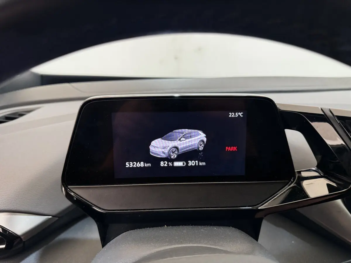 Écran numérique du tableau de bord montrant une Volkswagen ID.4 blanche en vue latérale, avec autonomie et température.