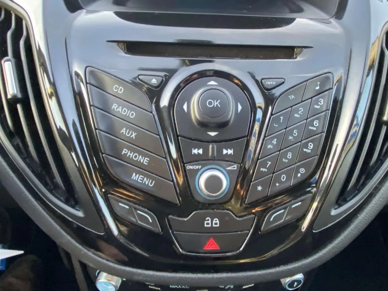 Vue rapprochée du tableau de bord noir brillant de la Ford B-MAX 2014, avec commandes audio et téléphone intégrées.