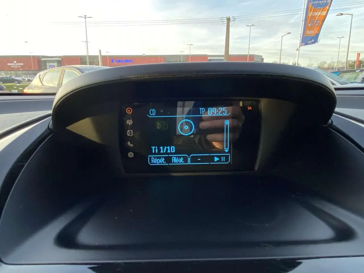 Écran central du tableau de bord de la Ford B-MAX 2014, affichant les commandes audio avec reflet extérieur.