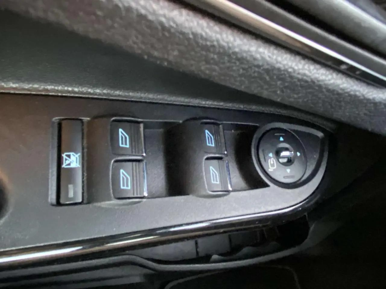Gros plan sur les commandes de lève-vitres et réglage des rétroviseurs côté conducteur d'une Ford B-MAX blanche.