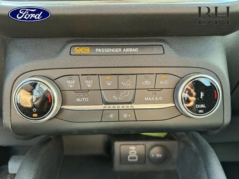 Vue rapprochée de la console de climatisation du Ford Kuga blanc glacier, avec commandes digitales et réglages bi-zone.