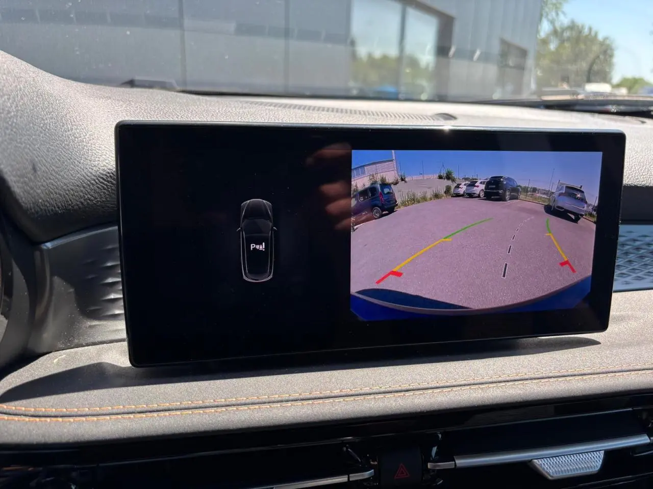 Écran tactile intérieur affichant la caméra de recul avec lignes de guidage du SUV Alfa Romeo Tonale blanc.