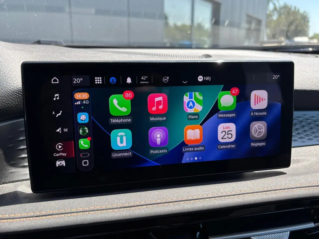 Écran tactile central affichant Apple CarPlay dans l'habitacle d'une Alfa Romeo Tonale 2025 blanche.