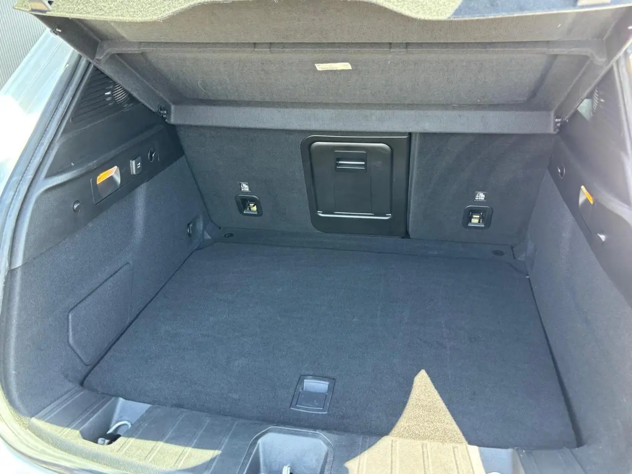 Vue intérieure du coffre spacieux de l'Alfa Romeo Tonale 1.5 Hybrid 130 Sprint TCT, revêtement noir et trappe à skis centrale.