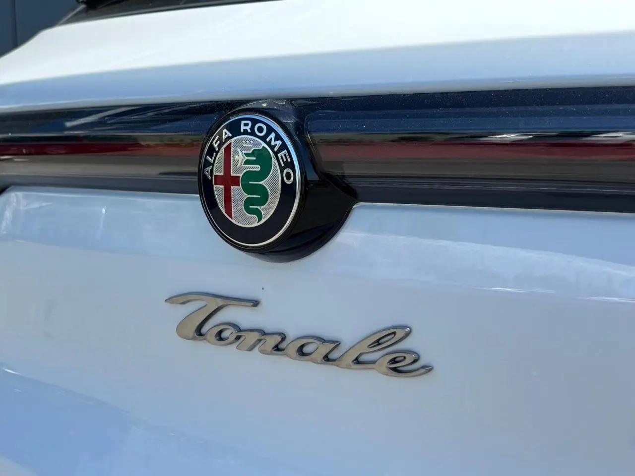 Gros plan sur l'arrière blanc d'une Alfa Romeo Tonale avec le logo et l'inscription Tonale en chrome.