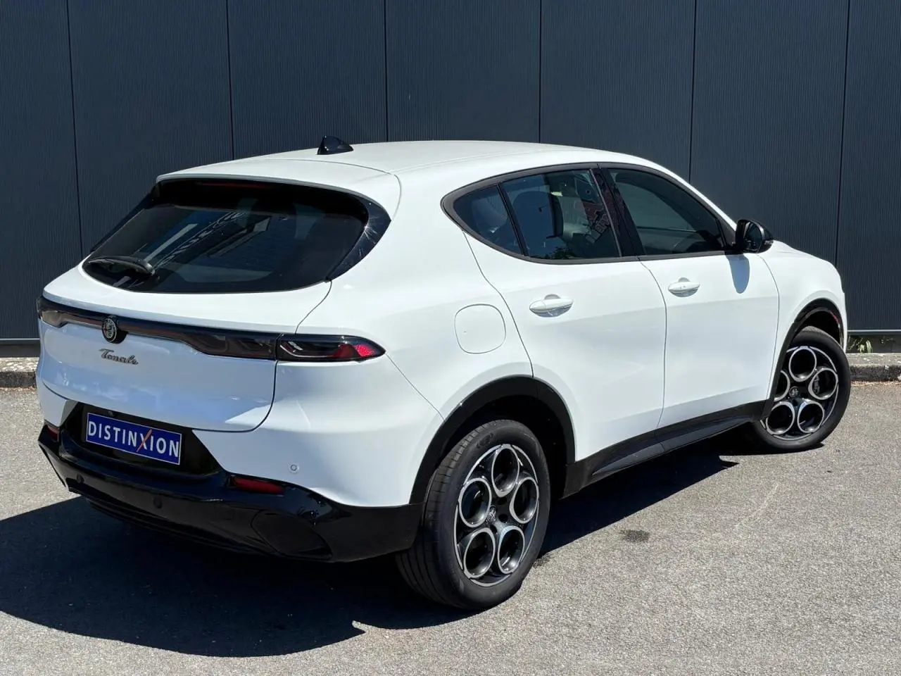 Vue 3/4 arrière droite d'un Alfa Romeo Tonale blanc métallisé avec jantes alliage 18 pouces et feux arrière full LED.