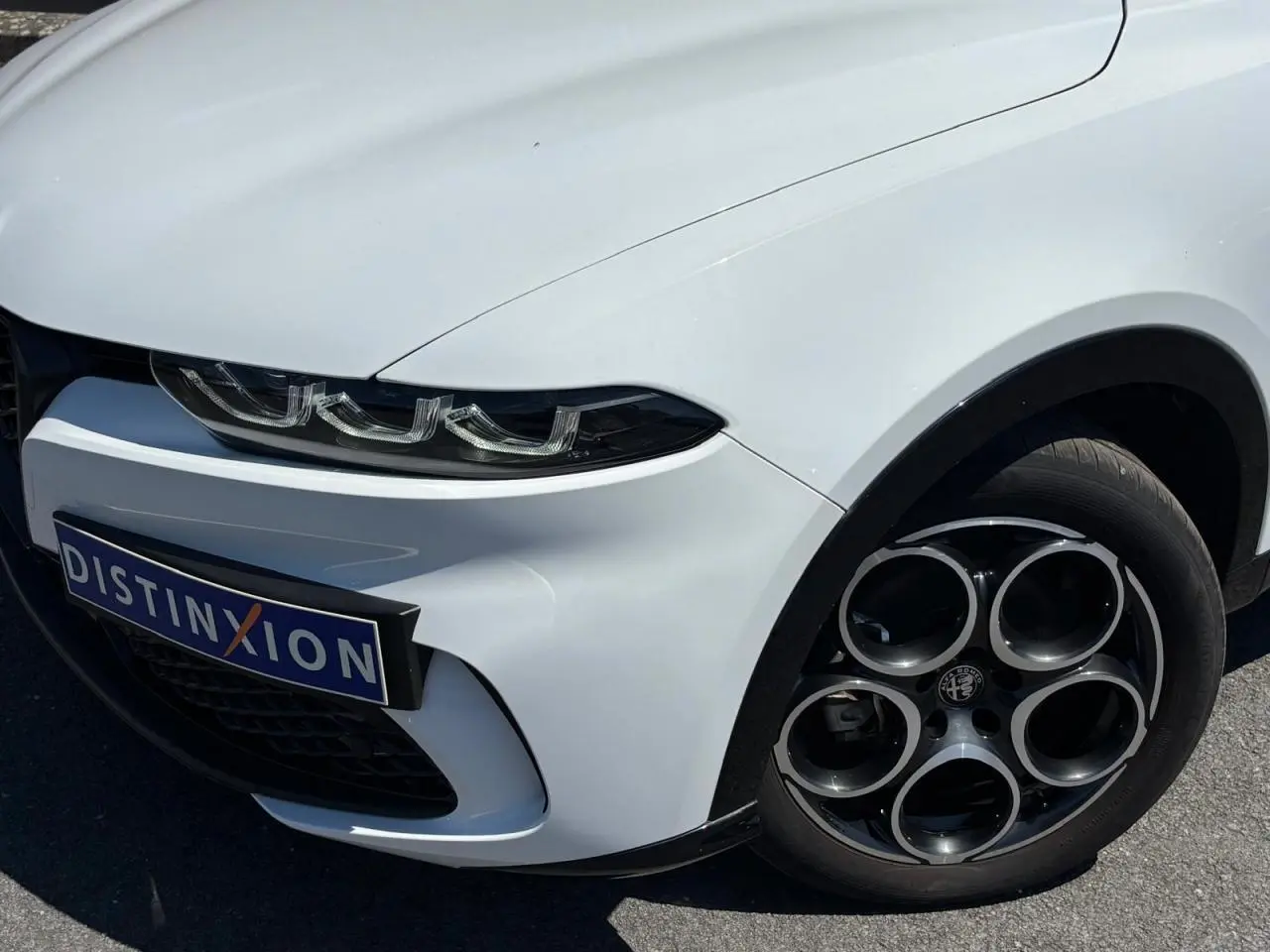 Vue 3/4 avant droit de l'Alfa Romeo Tonale blanc métallisé, mettant en valeur ses phares Full-LED et jantes alliage 18 pouces.
