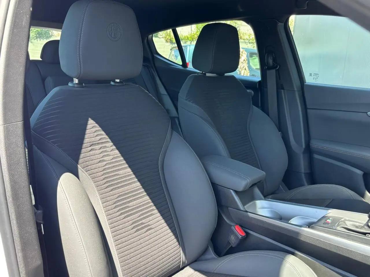 Vue intérieure côté droit de l'Alfa Romeo Tonale 2025, sièges noirs avec logo Alfa Romeo brodé sur les appuie-têtes.