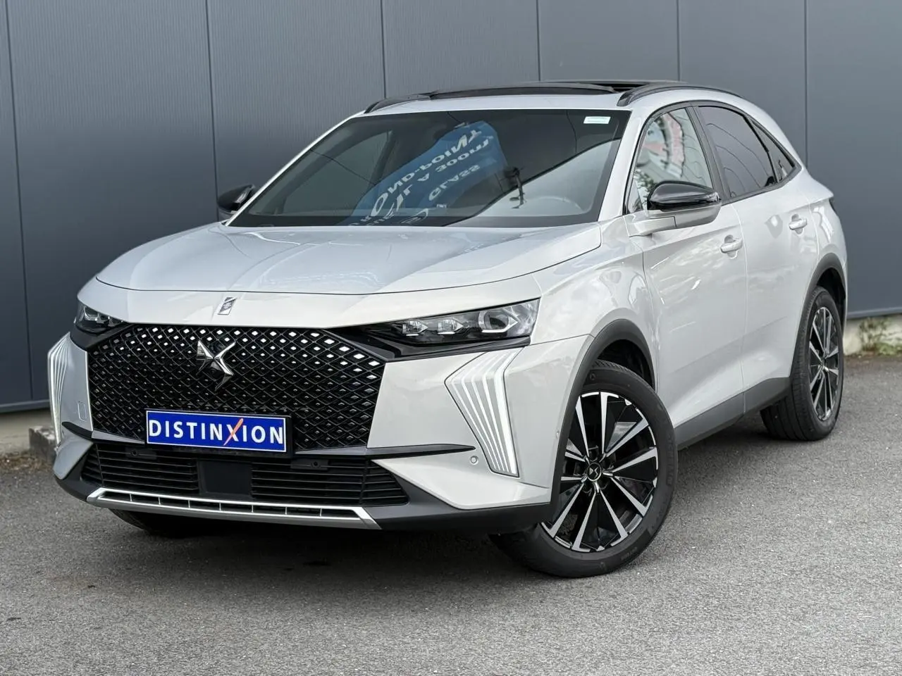 DS7 2025 Cristal Pearl en 3/4 avant droit, avec calandre noire distinctive et jantes alliage 19 pouces.