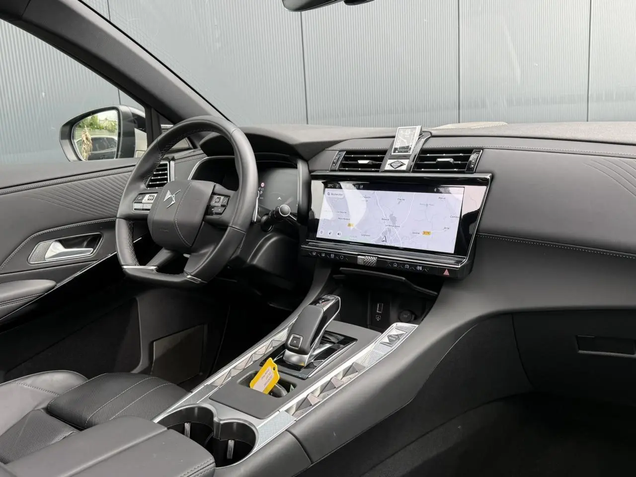 Vue intérieure côté conducteur du DS7 2025 avec tableau de bord noir, écran tactile et console centrale moderne.