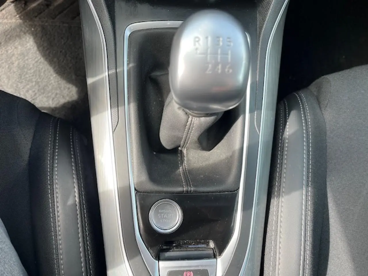 Vue rapprochée du levier de vitesse manuel et bouton start/stop de la Peugeot 308 gris clair, intérieur noir.