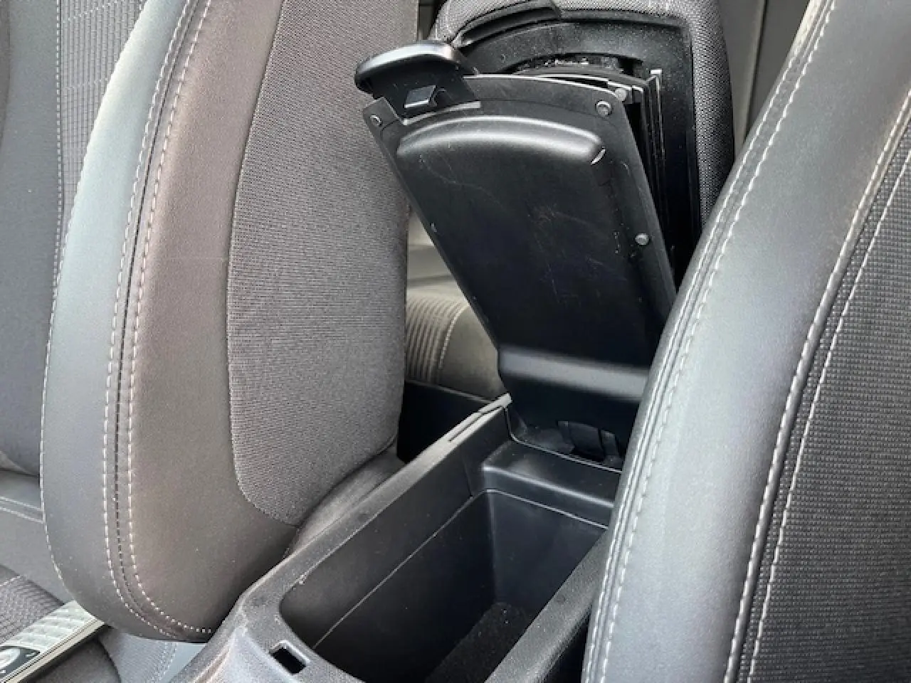 Gros plan sur l'accoudoir central avant ouvert entre les sièges avant gris foncé de la Peugeot 308 2018.