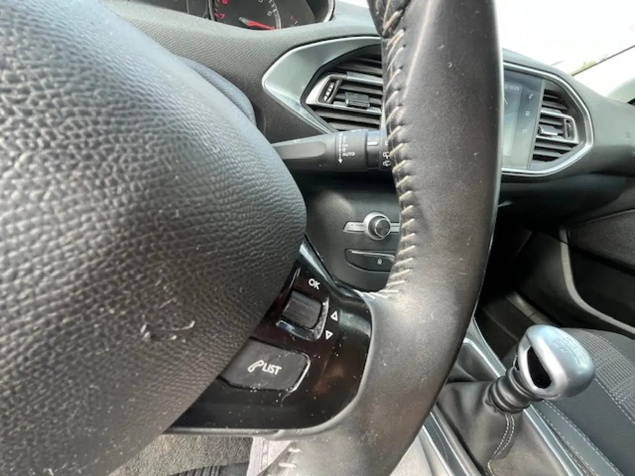 Vue rapprochée du volant et levier de vitesses manuel dans l’habitacle gris foncé d’une Peugeot 308 2018.