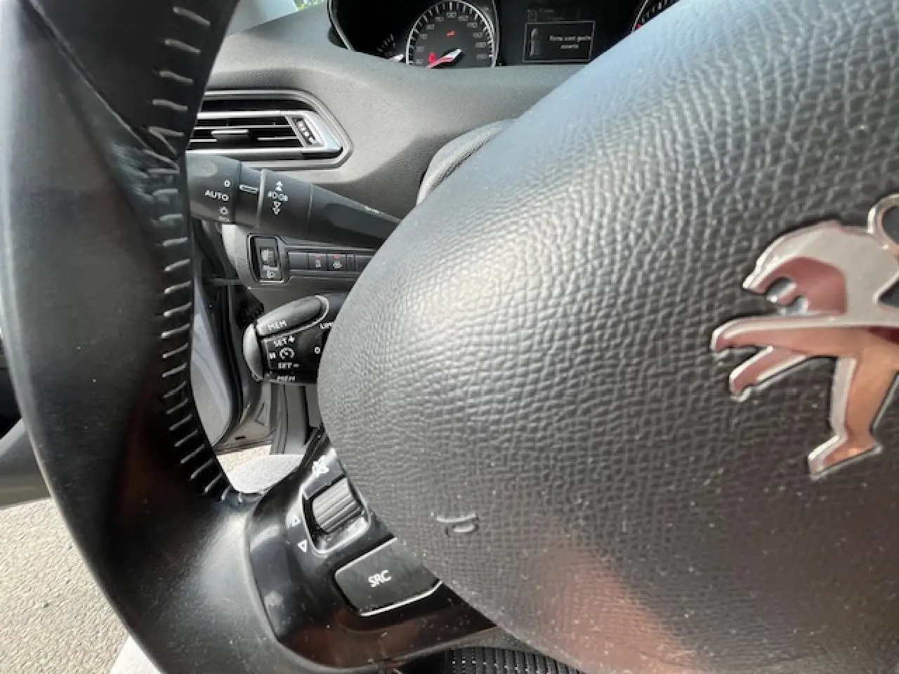 Gros plan sur le volant noir de la Peugeot 308 2018, avec commandes intégrées et tableau de bord partiellement visible.
