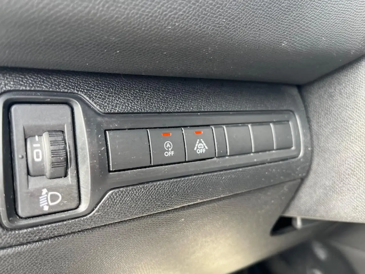 Gros plan sur les boutons de commande noirs du tableau de bord côté gauche de la Peugeot 308 gris clair.