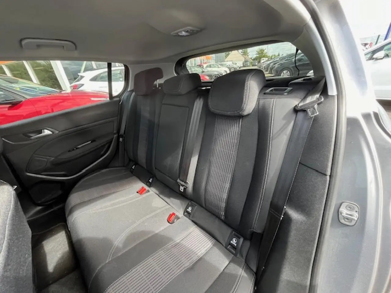 Vue intérieure arrière côté droit de la Peugeot 308 gris clair, montrant les sièges arrière en tissu noir avec ceintures de sécurité.