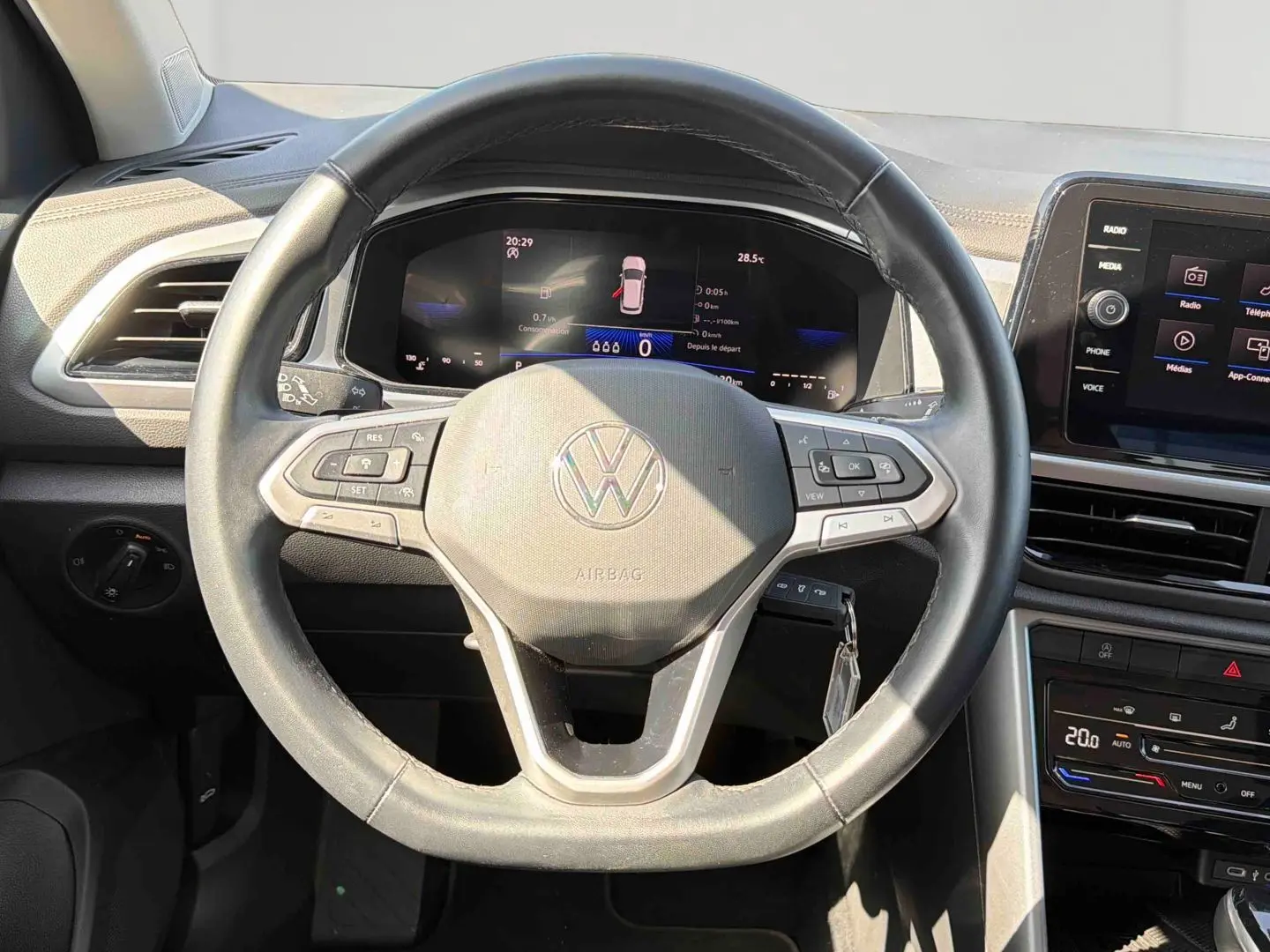 Vue intérieure centrée sur le volant cuir multifonctions du Volkswagen T-Roc 2025 avec tableau de bord digital et écran tactile.