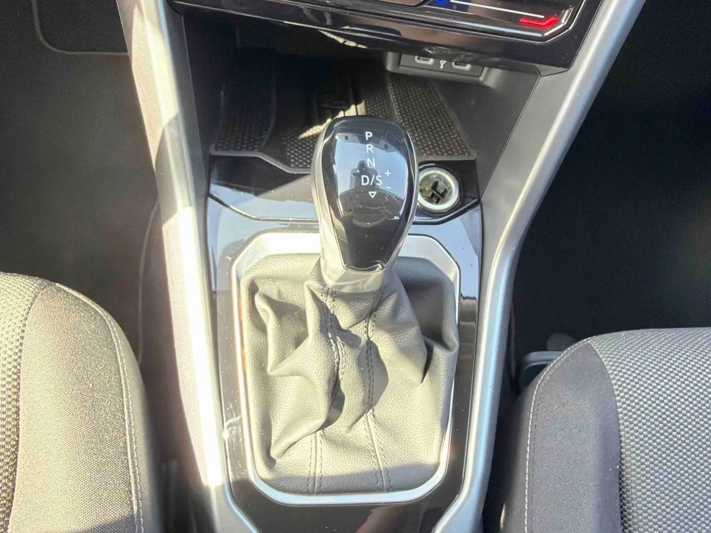 Vue rapprochée du levier de vitesse DSG7 noir entouré de cuir gris dans le Volkswagen T-Roc 2025 noir.