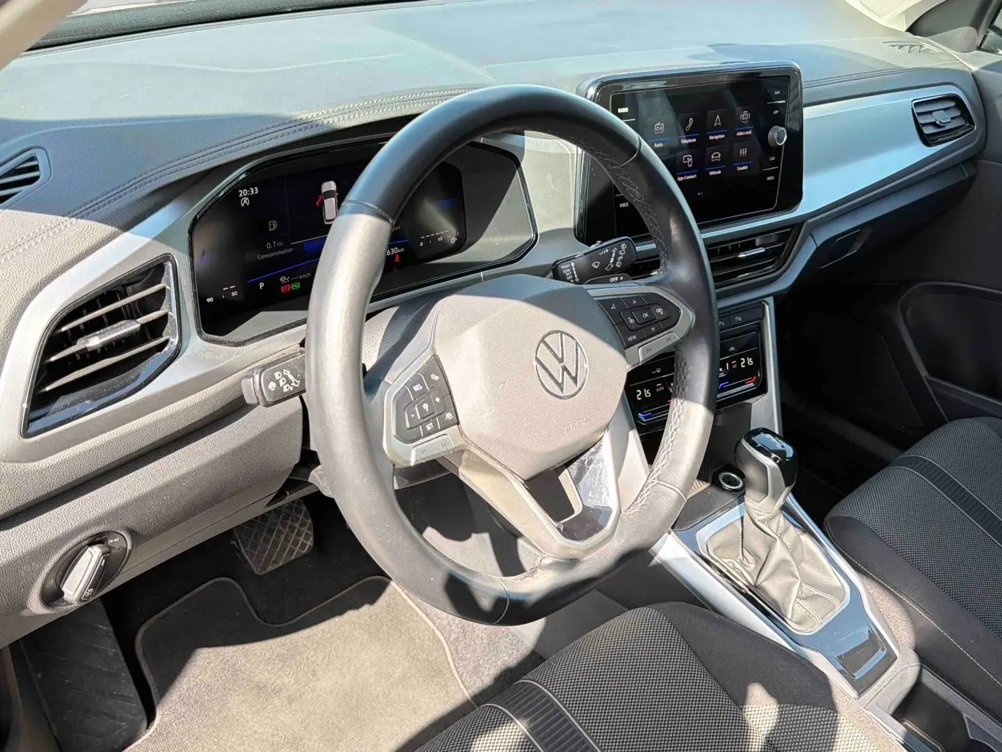 Vue intérieure du poste de conduite du Volkswagen T-Roc noir, avec volant cuir multifonctions et écran tactile central.