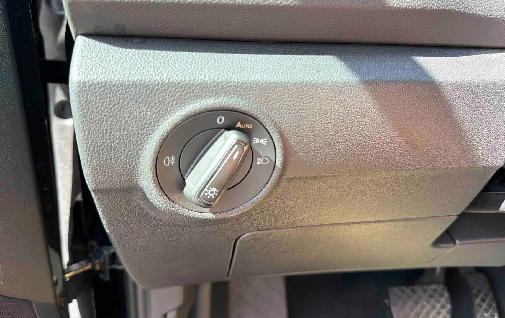 Gros plan sur le bouton de commande des phares dans l’habitacle noir du Volkswagen T-Roc 2025.