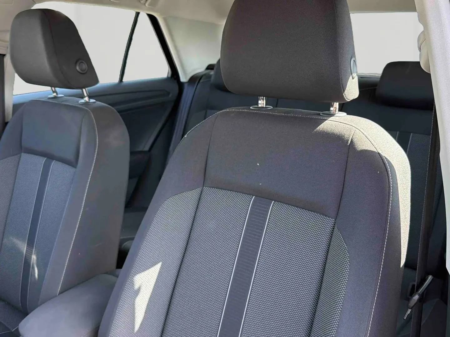 Gros plan sur les sièges avant gris foncé et tissu clair du Volkswagen T-Roc 2025, intérieur spacieux et lumineux.