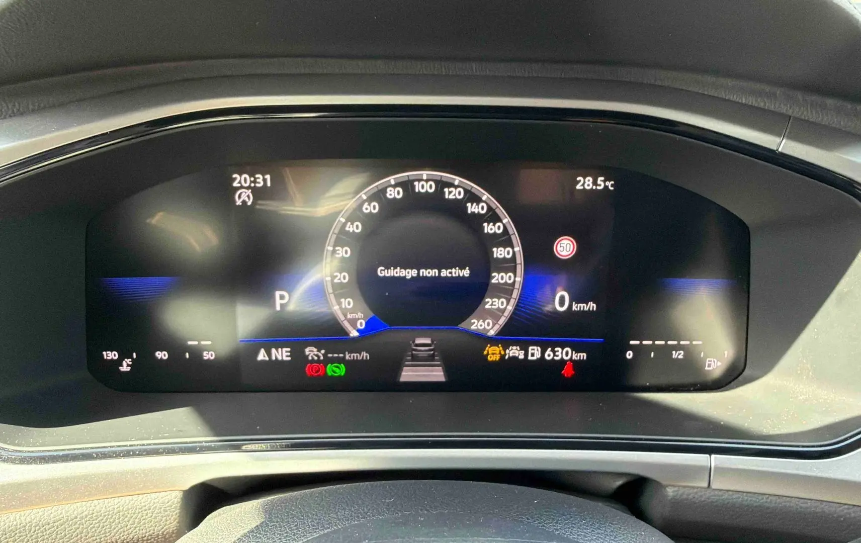 Tableau de bord digital du Volkswagen T-Roc 2025 affichant la vitesse et alertes, vu de face intérieur noir.