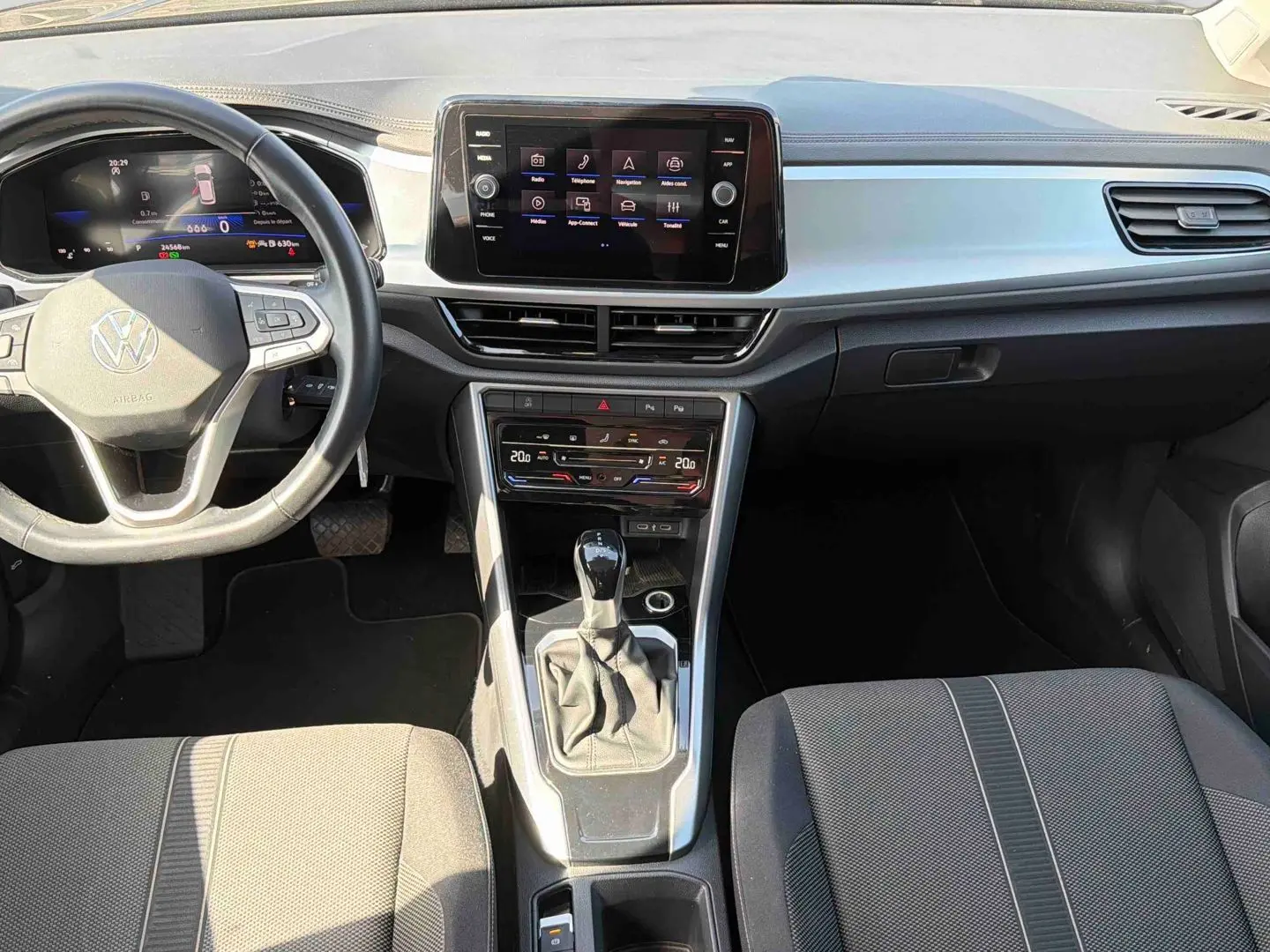 Vue intérieure avant du Volkswagen T-Roc 2025 avec tableau de bord moderne, écran tactile et levier de vitesse manuel.