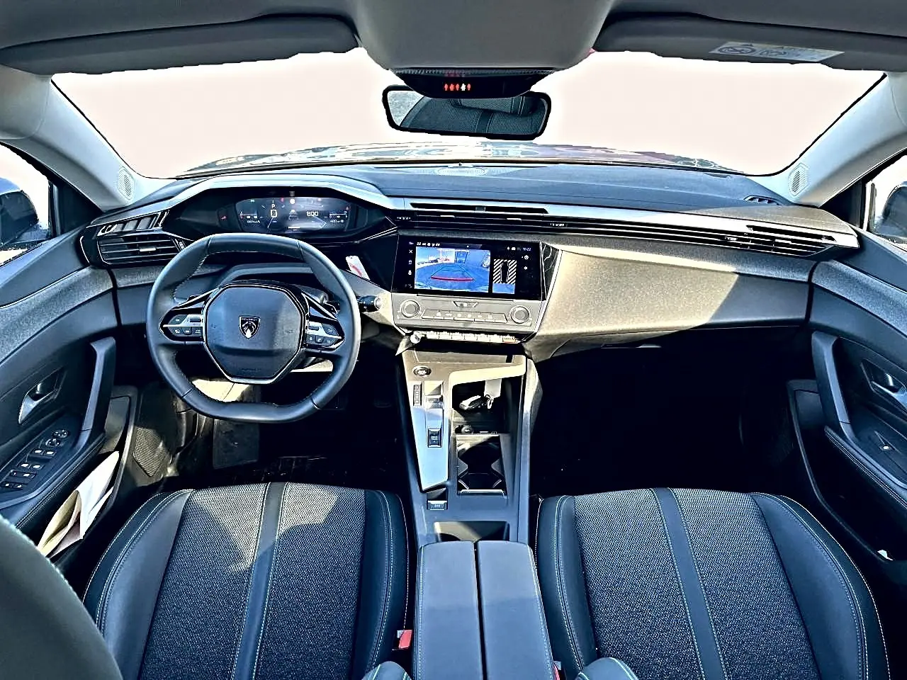 Vue intérieure avant de la Peugeot 308 gris selenium, tableau de bord moderne avec écran tactile et volant multifonction.