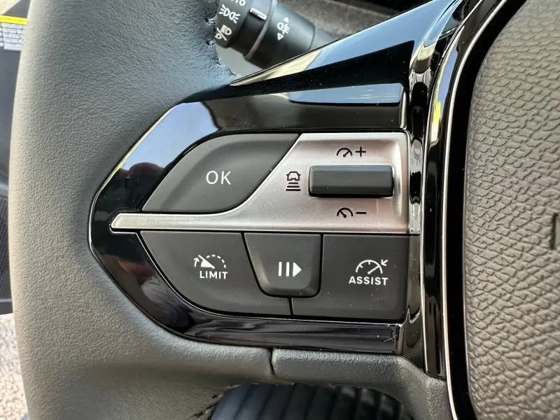 Gros plan sur les commandes multifonctions noires et argentées du volant côté gauche du Peugeot 308 gris Artense.