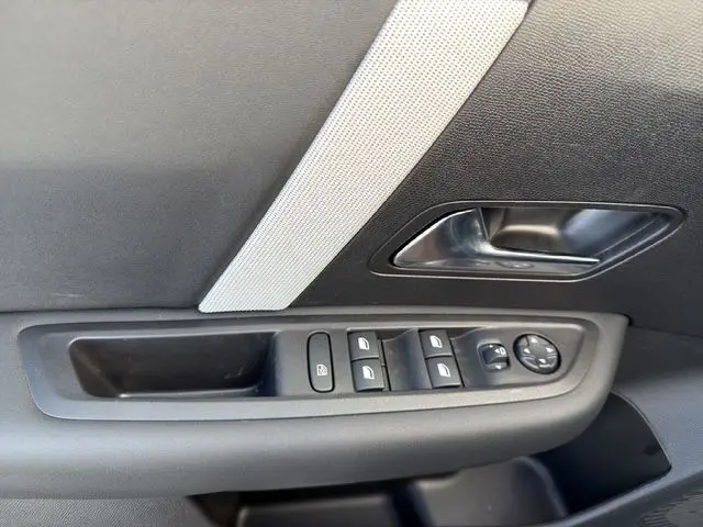 Gros plan sur la commande des vitres et la poignée intérieure côté gauche d'une Citroën C4 Hybrid 145 gris Mercury.