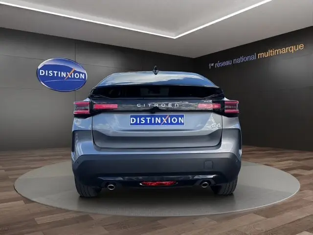 Vue arrière d'une Citroën C4 Hybrid 145 gris Mercury, avec feux LED et double sortie d'échappement visible en showroom.