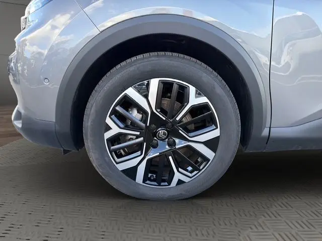 Gros plan sur l'aile avant gauche gris Mercury d'une Citroën C4 Hybrid 2025, avec détail du passage de roue et bas de caisse noir mat.