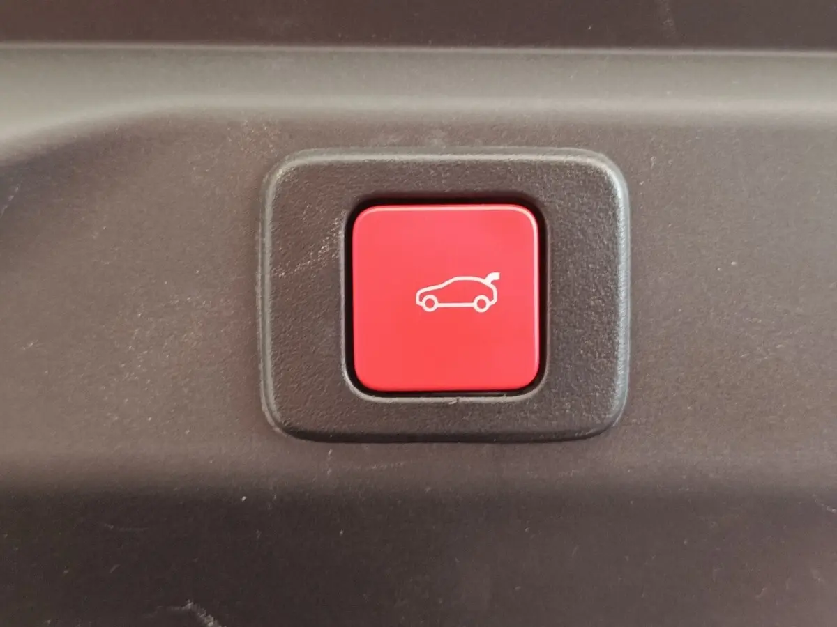 Bouton rouge d'ouverture électrique du coffre sur un Peugeot 3008 1.2 Hybrid 136 E-DCS6 GT, vue rapprochée.