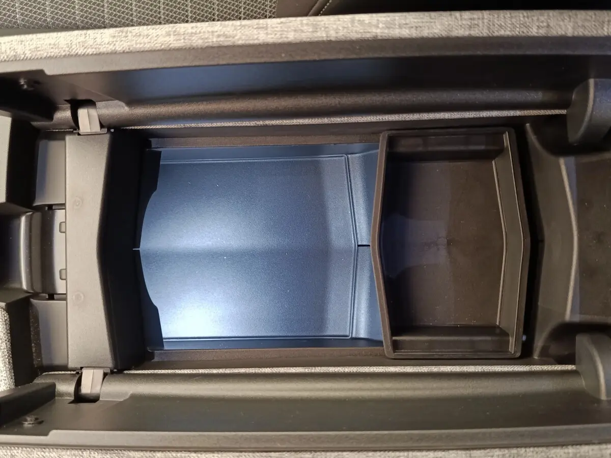 Vue plongeante sur le rangement central intérieur du Peugeot 3008 1.2 Hybrid 136 GT, avec compartiment bleu et noir.