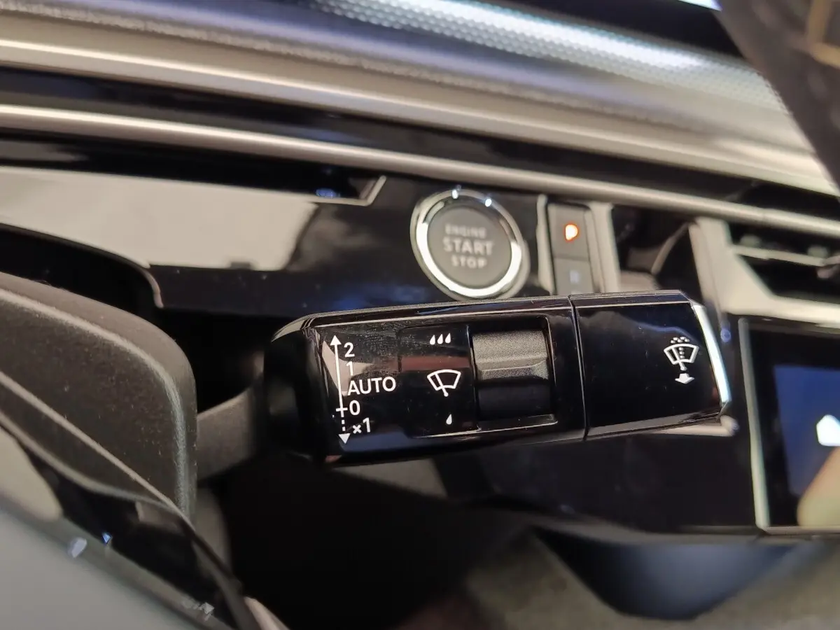 Gros plan sur la commande d’essuie-glace noire dans l’habitacle du Peugeot 3008 bleu, avec bouton démarrage visible.