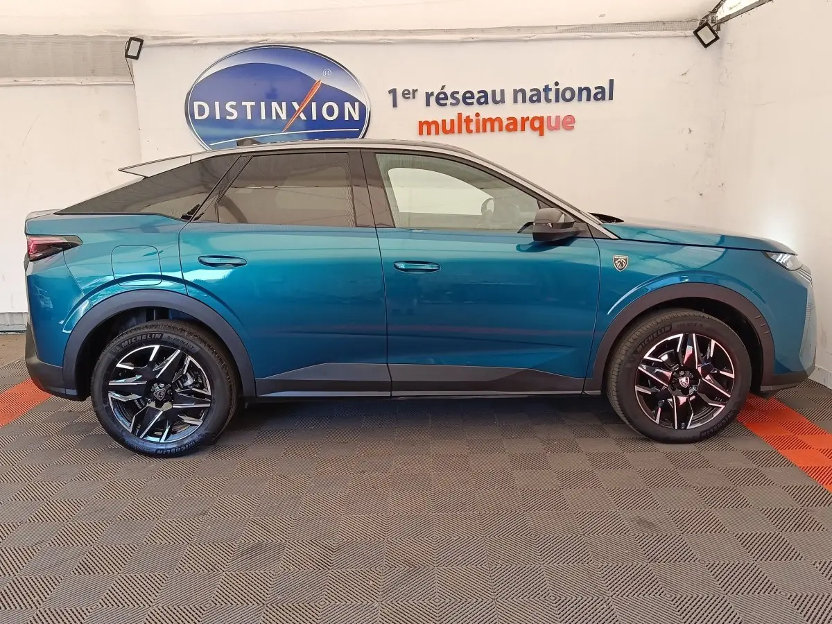 Profil droit du Peugeot 3008 hybride bleu 2025 avec jantes noires et toit noir, en intérieur showroom.