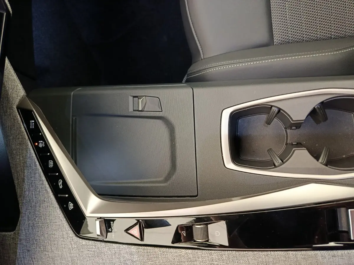 Vue rapprochée de la console centrale grise et noire du Peugeot 3008 1.2 HYBRID 136 E-DCS6 GT avec porte-gobelets.