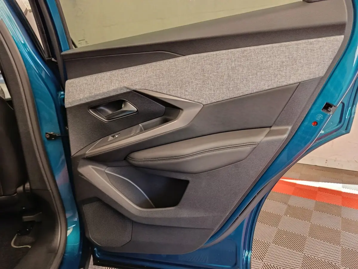 Vue intérieure de la porte arrière gauche bleu métallisé du Peugeot 3008 1.2 Hybrid 136 E-DCS6 GT avec garniture tissu et cuir.